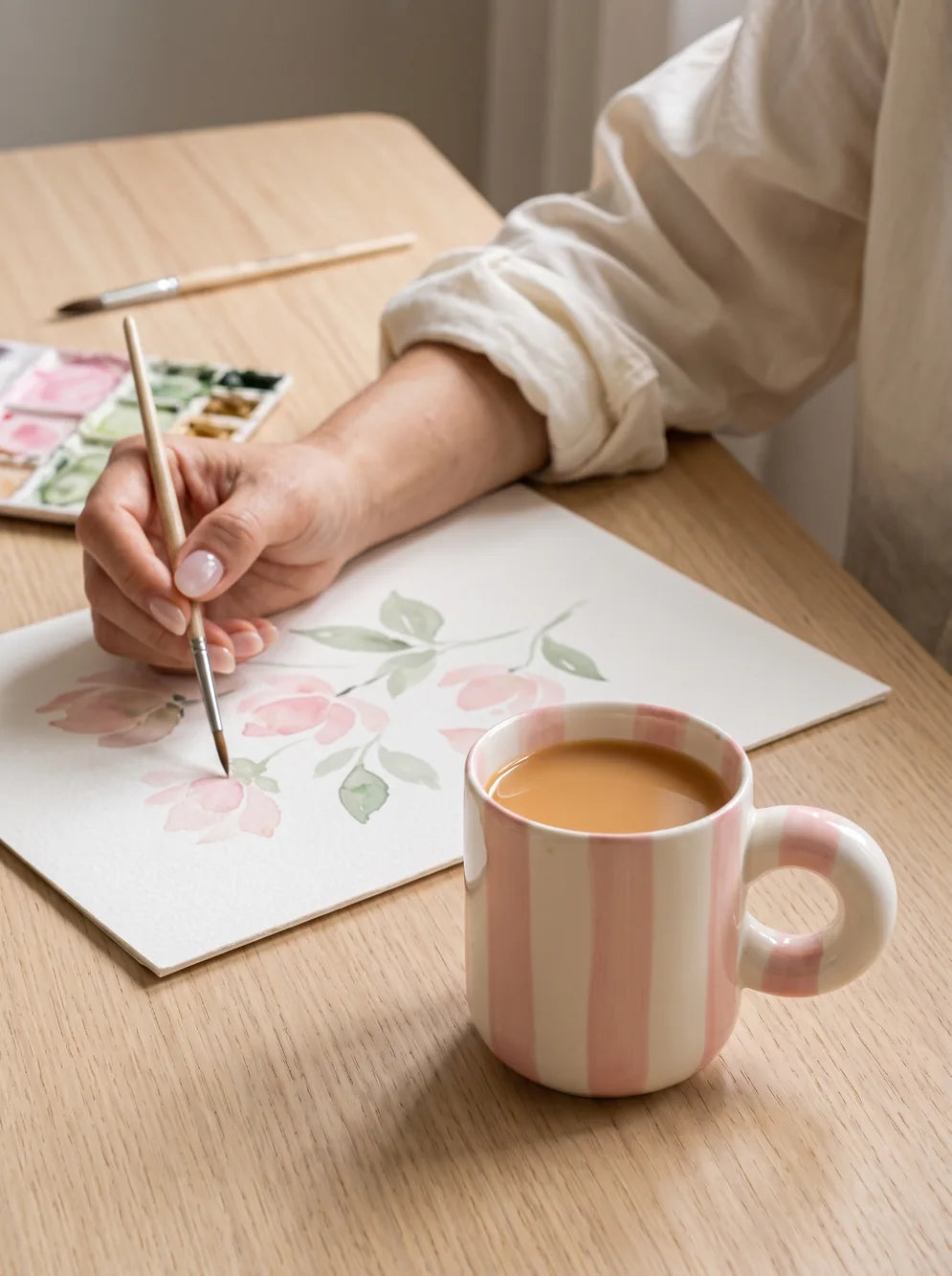 Watercolour flowers, a paintbrush, and a mug of milky coffee.