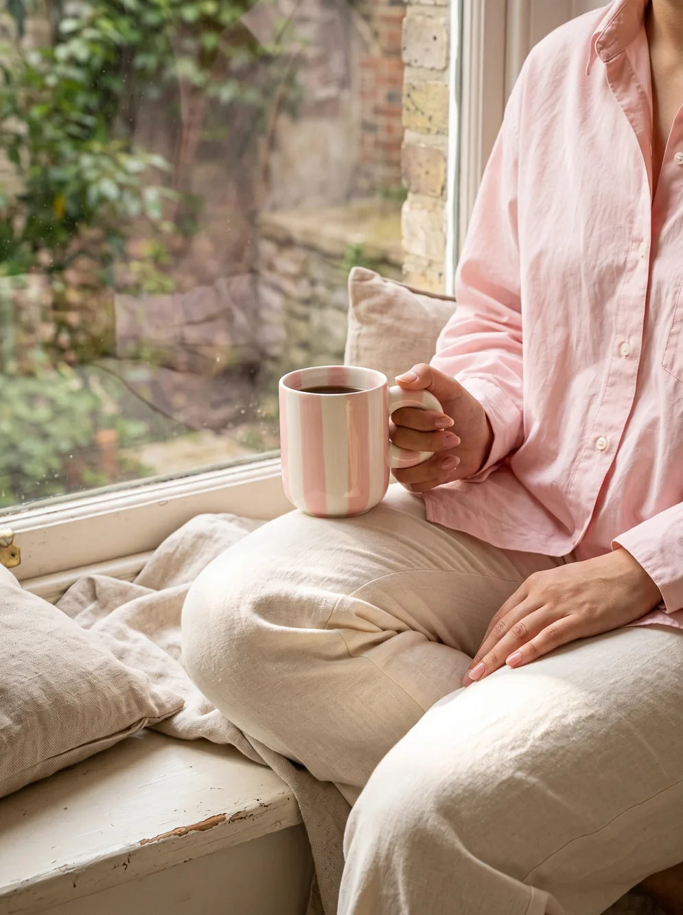 A woman sitting comfortably by the window with her mug.